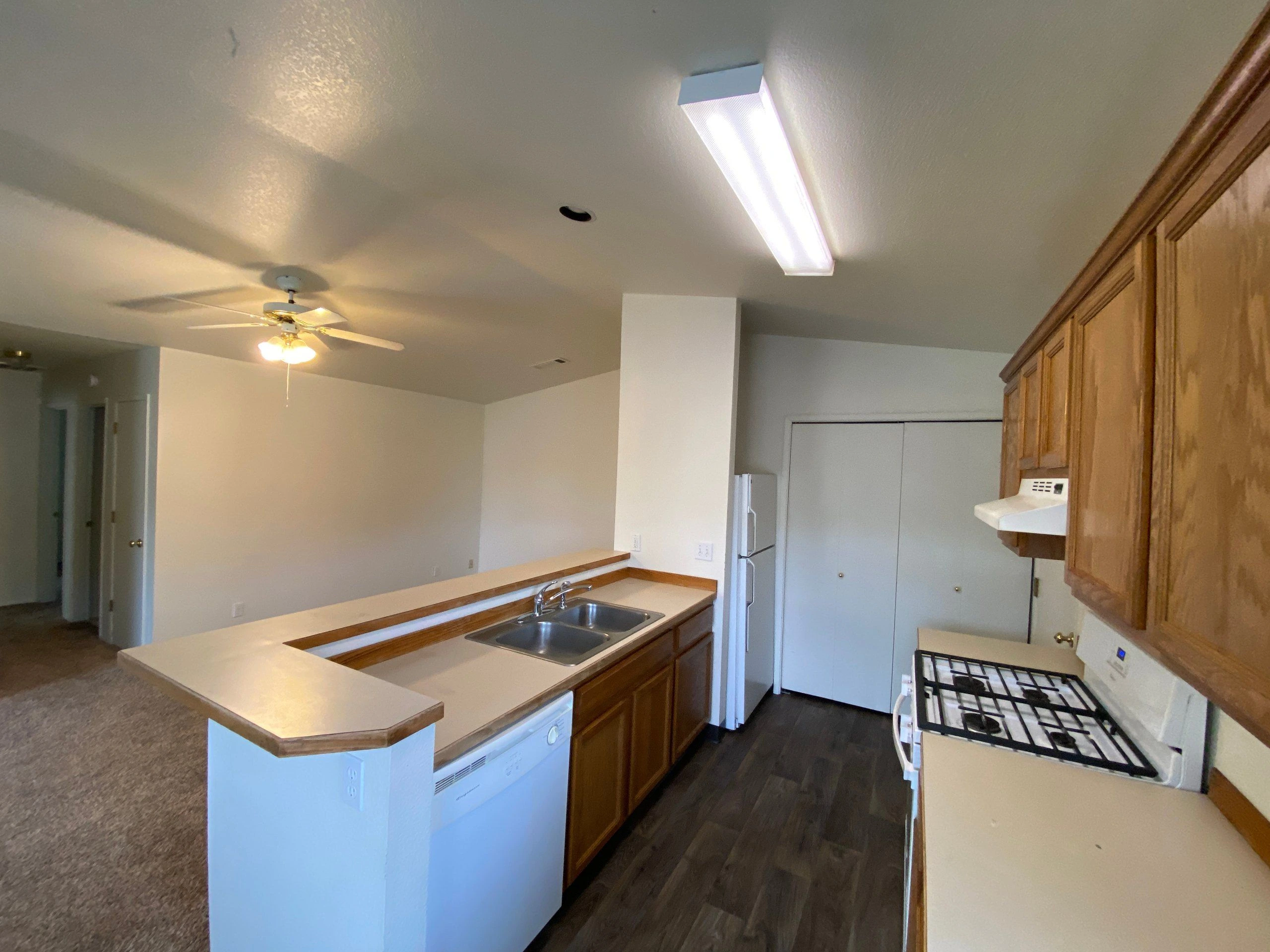 A kitchen with wood cabinets, a double-basin sink, a gas stove, and a refrigerator.