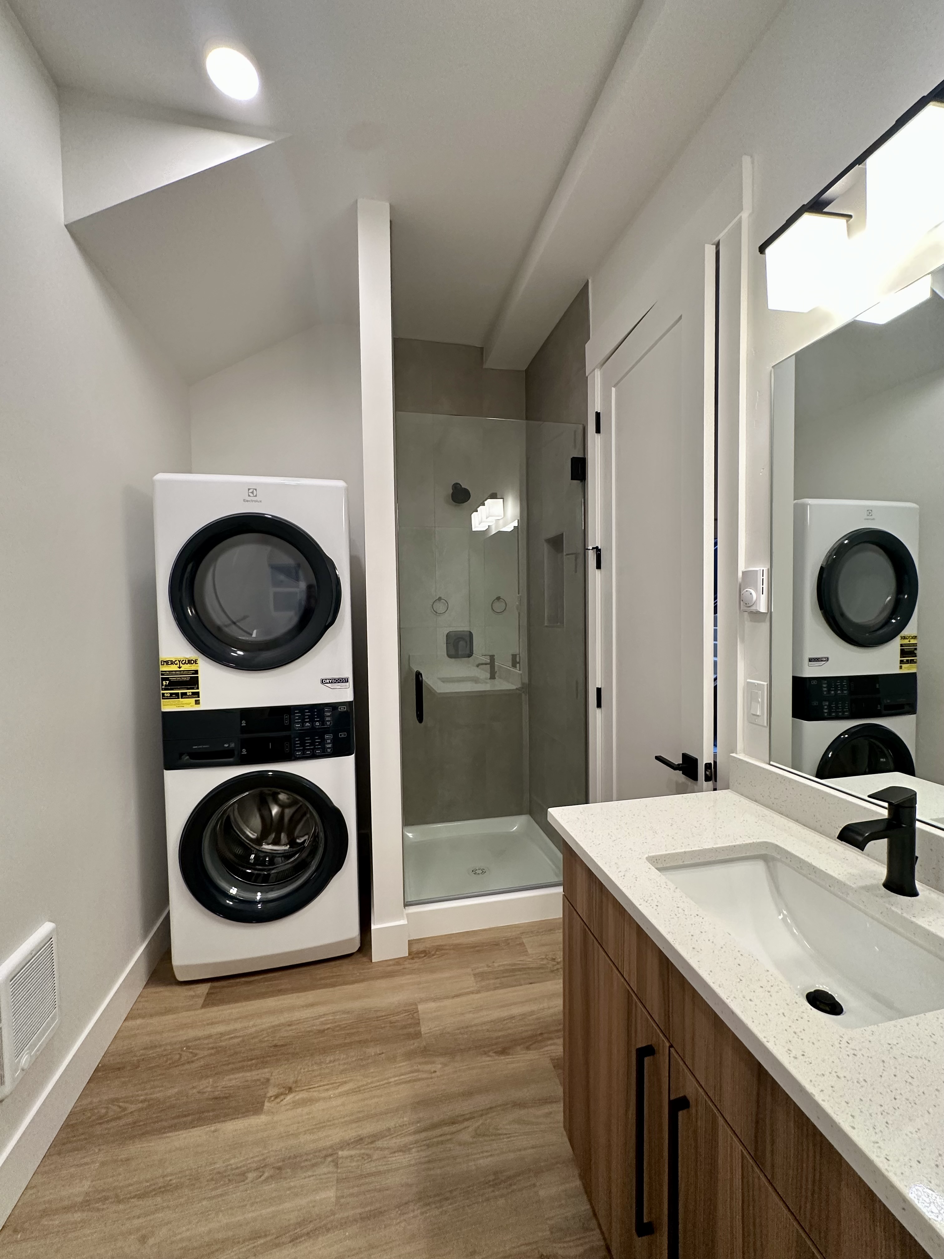 Bathroom with a stacked washer and dryer, glass shower, mirrored cabinet, and sink vanity.