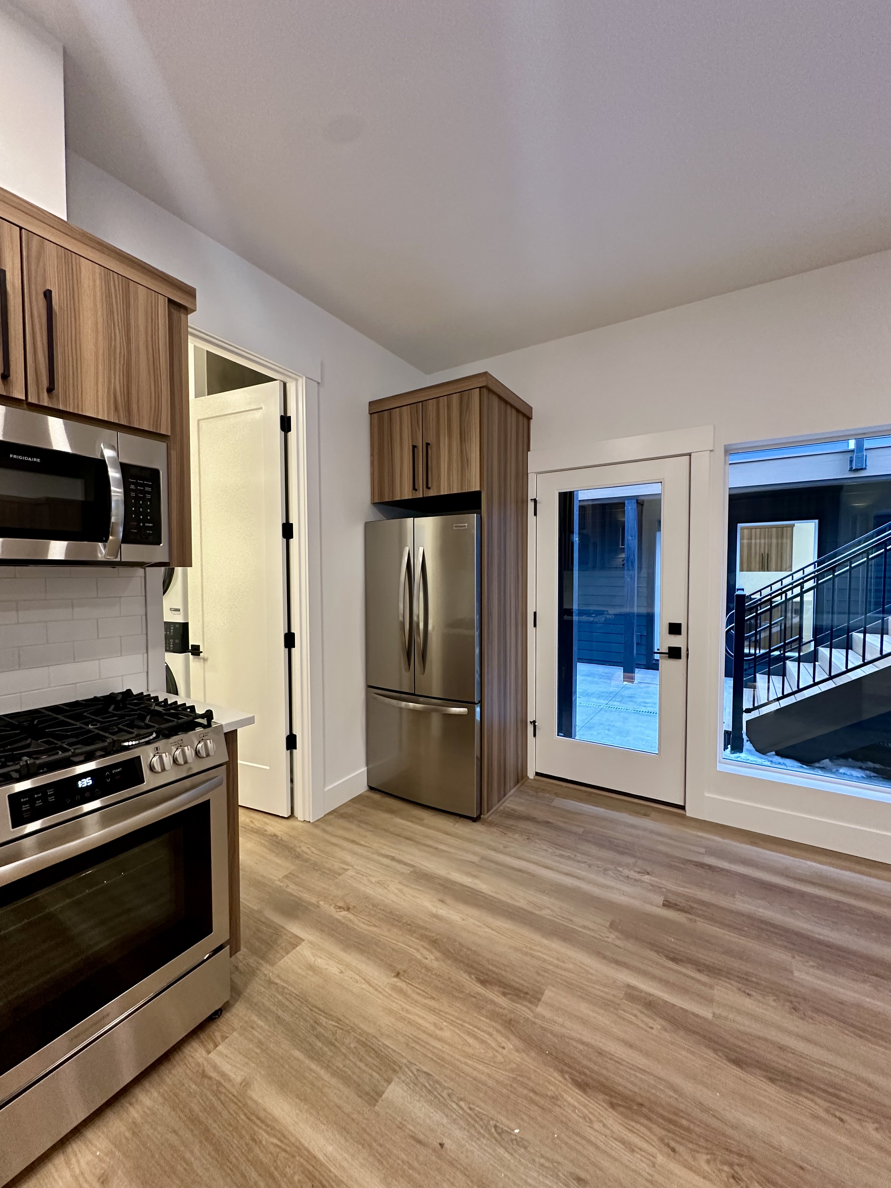 Kitchen with wood cabinets, stainless steel appliances, a gas range, a refrigerator, a glass door, and wood-look flooring.