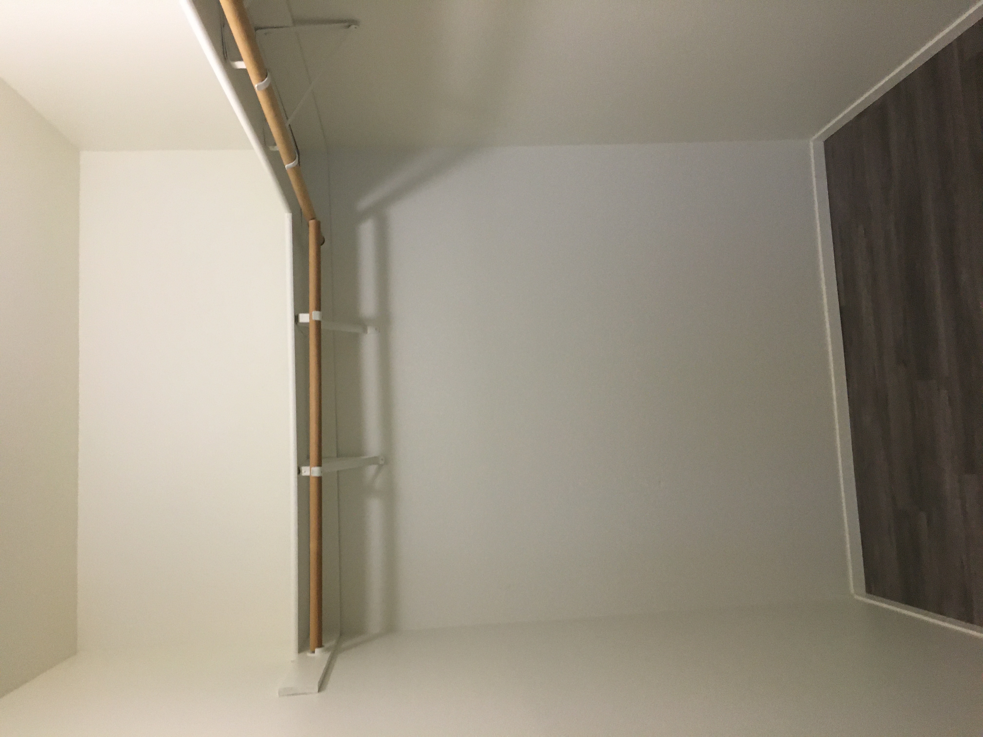 A wooden rail runs beneath a broad white ledge on wall-mounted brackets, above a dark doorway.